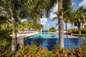 a swimming pool surrounded by palm trees and flowers at Morea SXM in Simpson Bay