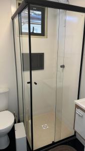 een glazen douche in een badkamer met toilet bij Box 01 a 950 mt do mar, ar- condicionado, TV smart, cozinha privativa in Itapema