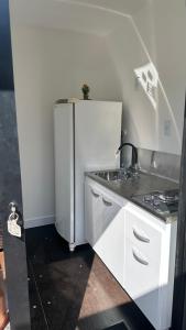 een keuken met een witte koelkast en een fornuis bij Box 01 a 950 mt do mar, ar- condicionado, TV smart, cozinha privativa in Itapema