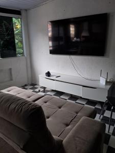 a living room with a couch and a flat screen tv at Casa Confortável Próximo a Lindas Praias in São Sebastião