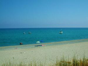 a beach with umbrellas and boats in the water at Diving Center Punta Stilo in Stilo