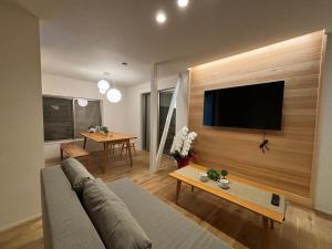 un soggiorno con un divano e una TV a parete di とまるん長島 a Kuwana