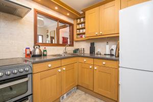 eine Küche mit Holzschränken und einem weißen Kühlschrank in der Unterkunft Ivy Cottage in Haverfordwest