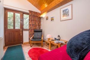 Zimmer mit einem roten Bett, einem Stuhl und einem Tisch in der Unterkunft Ivy Cottage in Haverfordwest