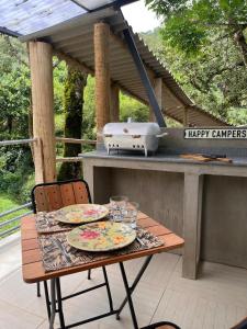 a picnic table with plates and glasses on a grill at Refugio Jabuticaba - CASA DA ÁRVORE - Conforto em meio a natureza in Santo Antônio do Pinhal