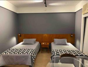 a room with two beds and a table at Suíte na região dos hospitais in Sao Paulo