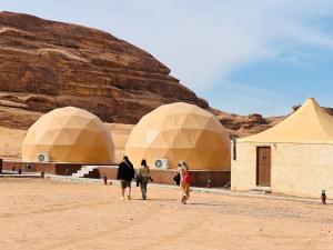 three people walking in front of domes in the desert at Rum relaxation luxury camp in Wadi Rum +64 photos