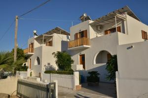 ein weißes Haus mit einem Zaun davor in der Unterkunft Theoni Apartments Kastraki Naxos in Kastraki Naxos