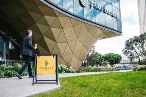 a man walks past a sign in front of a building at Pullman Auckland Airport in Auckland