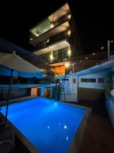 a large blue swimming pool in front of a building at night at Casa Mismaloya Primavera in Puerto Vallarta