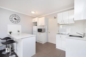 ブリスベンにあるCity Skyline View, Urban Retreatの白いキャビネットと壁掛け時計付きのキッチン +3枚の写真