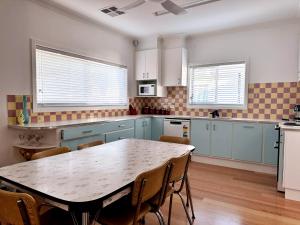 a kitchen with blue cabinets and a table with chairs at Happy Stays - Retro Haven in Shepparton