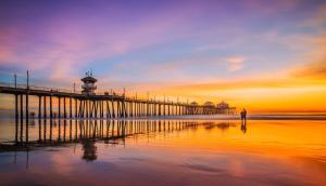 a man standing on the beach near a pier at Modern Family Haven - Minutes from Disney Magic-OC in Midway City