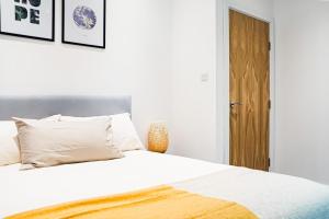 ハウンズローにあるSomerville Apartment London Heathrowの白いシーツと枕が備わったベッドのある寝室