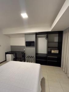 a bedroom with a white bed and a table and chairs at Loft Celita Franca in Feira de Santana