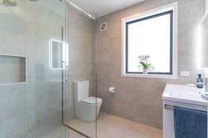 um banheiro com vaso sanitário e chuveiro de vidro em The Zoey suite em Maraetai