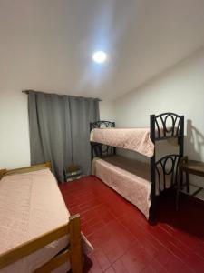 a room with two bunk beds and a red tile floor at Casa a 1 cuadra del Río San Antonio in San Antonio de Arredondo