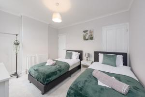 zwei Betten in einem Schlafzimmer mit weißen Wänden in der Unterkunft Medway, Rochester Stays Living - Contractors, Family, Free Parking, Garden, Sleeps up to 6 guests in Wainscot