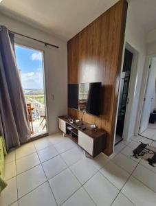 a living room with a television and a large window at Apto Araçagy Ilha de São Luis in São-José-do-Ribamar
