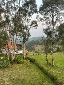 a field with trees and a car in the distance at Cabana Trinca Ferro in São Pedro de Alcântara +18 photos