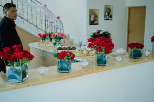 a man standing behind a counter with red flowers in vases at Pensiunea Coca in Baile Felix
