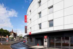 a white building on a street next to a road at ibis Genève Petit Lancy in Geneva