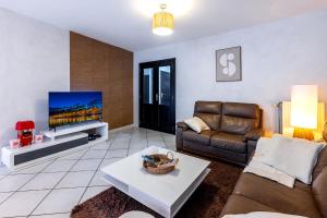 un salon avec un canapé et une télévision dans l'établissement Séjour lodge Namur, à Namur