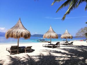 a group of umbrellas and chairs on a beach at Basios Place Tourist Inn by RedDoorz in San Vicente