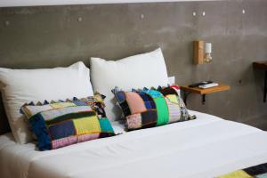 a bed with white sheets and pillows on it with a table at Casa do Chafariz Velho in Angra do Heroísmo