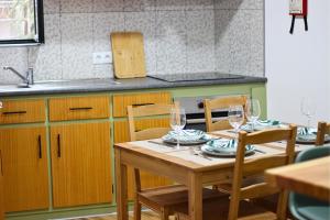 a kitchen with a wooden table and chairs with glasses at Casa do Chafariz Velho in Angra do Heroísmo
