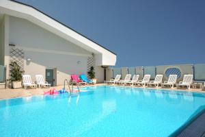 a large swimming pool with chairs and a water slide at Hotel Principe in Cattolica