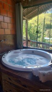 a large tub in a room with a window at Chalés Fenix in Santo Antônio do Pinhal