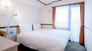 a bedroom with a white bed and a window at Toyoko Inn Hokkaido Sapporo-eki Nishi-guchi Hokudai Mae in Sapporo