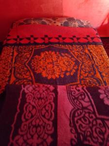 un lit avec une couverture colorée dessus dans l'établissement Obira Oasis Merzouga Camp, à Merzouga