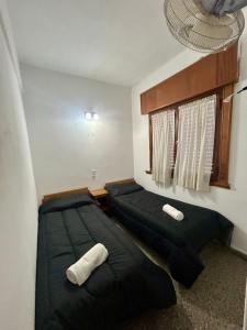 two beds in a room with black pillows at Hotel Zenit in Mar de Ajó