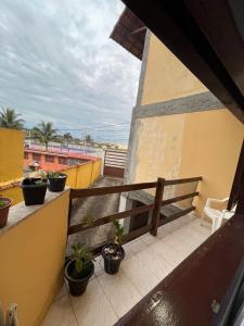a balcony with a bench and potted plants on it at Flat na beira da praia in Maricá