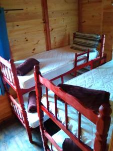 three bunk beds in a room with wooden walls at Cabañas Recanto do pepe in Santa Vitória do Palmar
