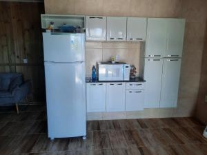 a kitchen with white cabinets and a white refrigerator at Servidão 1619 in Palhoça
