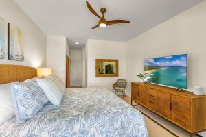 a bedroom with a bed and a flat screen tv at Poipu Sands 437: 2BR Ocean View Condo w/ A/C, pool in Koloa