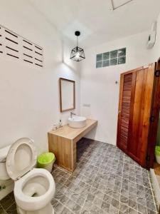 a bathroom with a toilet and a sink and a mirror at Baan Pong Tara in Suan Phung