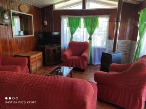 Cabaña el Diuco في كونياريبي: غرفة معيشة فيها كرسيين احمر وتلفزيون