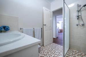 ein weißes Badezimmer mit Waschbecken und Dusche in der Unterkunft A1 Airport Haven - Quick Access, Comfy & Free Parking in Perth + 19 Fotos