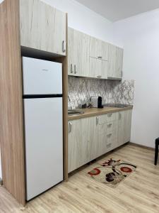 a kitchen with a white refrigerator and wooden cabinets at Grey House in Vălenii de Munte