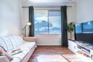 ein Wohnzimmer mit Couch und Flachbildfernseher in der Unterkunft A1 Airport Haven - Quick Access, Comfy & Free Parking in Perth