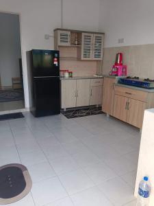 a kitchen with a black refrigerator and a white tile floor at Auni Homestay in Raub +1 photo