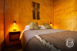 a bedroom with a bed in a wooden room at Cabañas Leufu in Futaleufu
