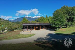 a large building with mountains in the background at Cabañas Leufu in Futaleufu