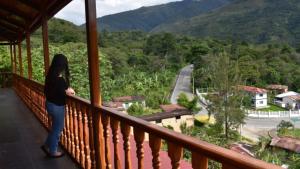 a woman standing on a balcony looking at a road at Waranway Lodge Huayopata in Quillabamba