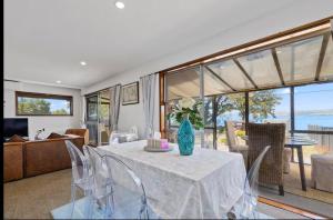 a living room with a table with a vase of flowers on it at Fabulous Lake Front House-Private lake access in Rotorua
