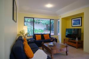 un soggiorno con un divano blu e una TV di Airport 6BR Haven - Quiet Yard & AC a Perth